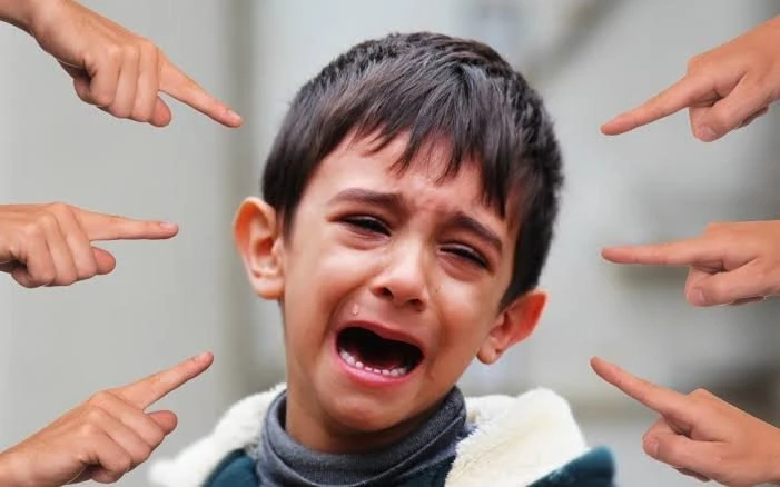 A boy cries while several hands point at him from all sides